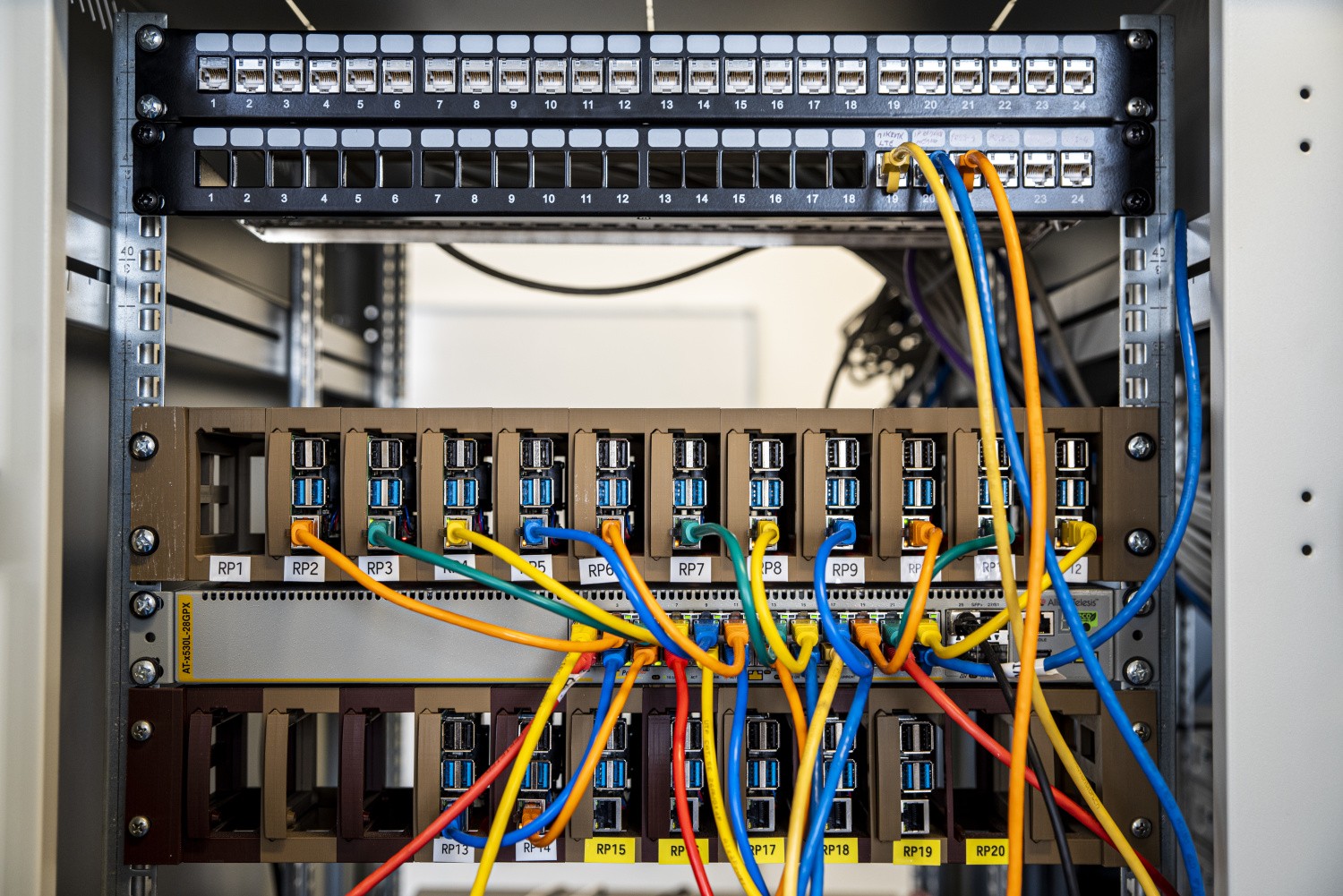 Network rack in ComTech Lab with patch panels, connected fibre cables and research equipment.